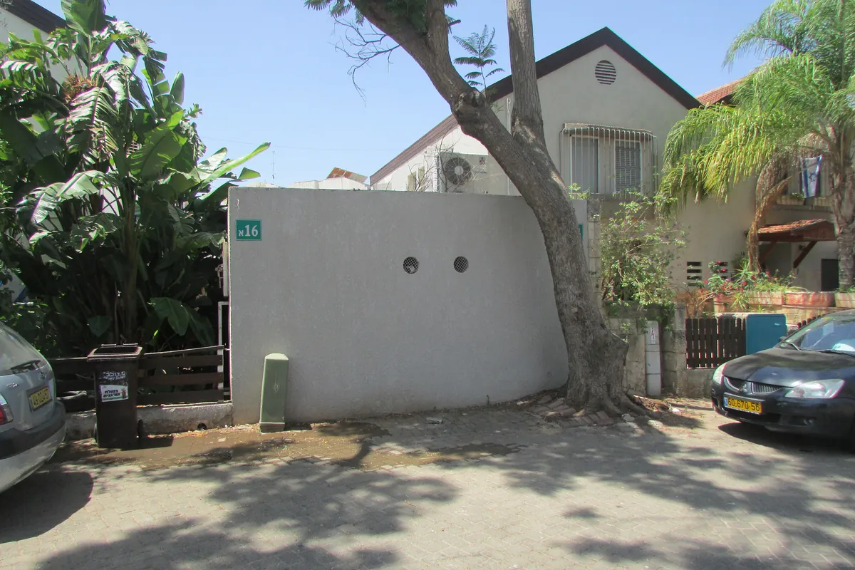 A house, garden wall and trees on a street in the Hadarim neighbourhood of Kfar Saba